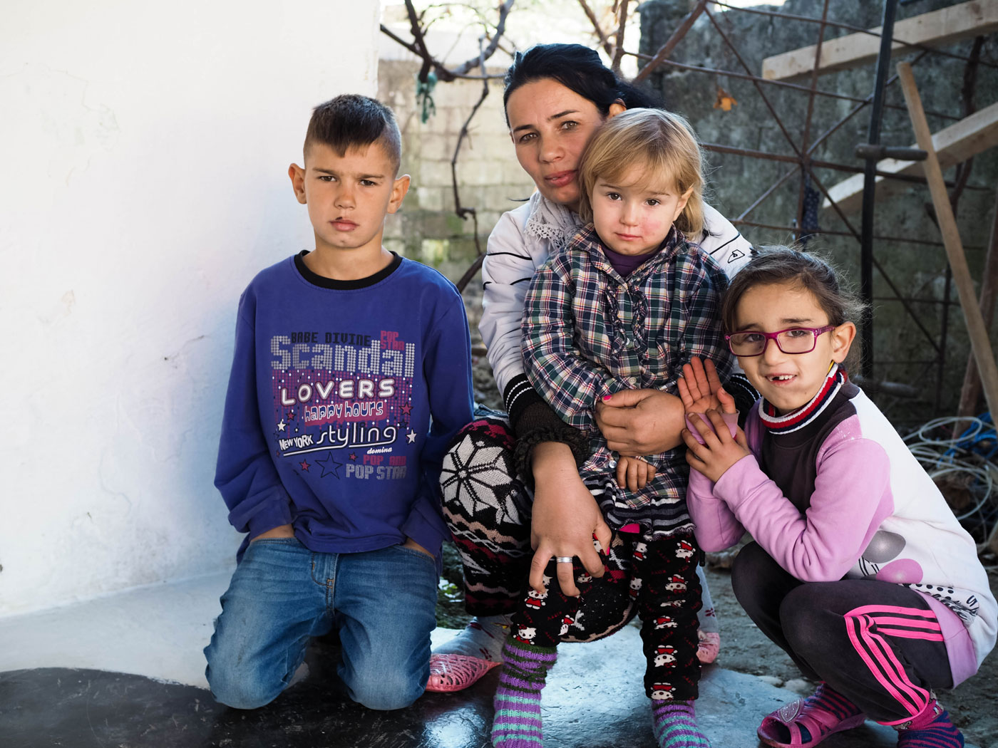 En albansk alvorlig mor med de tre barna sine på fanget og rundt seg i fattige omgivelser. 